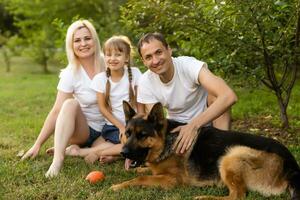 retrato de un extendido familia con su mascota perro sentado a el parque foto