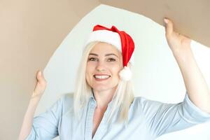 christmas, delivery and winter holidays concept - happy young woman in santa helper hat looking into open gift box photo