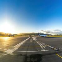 AI generated panoramic view of an airport runway with planes parked and in motion photo