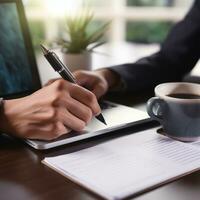 AI generated person hand holding a pen, signing a contract on desk with a laptop and coffee cup in the background photo