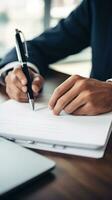 AI generated person hand holding a pen, signing a contract on desk with a laptop and coffee cup in the background photo