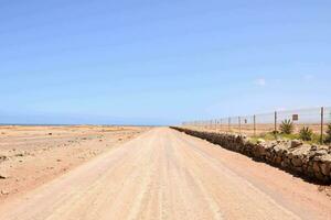 un suciedad la carretera en el medio de un Desierto con un rock cerca foto