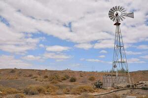 a windmill in the desert with a blue sky photo