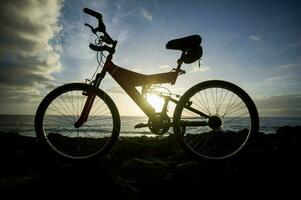 a bicycle is parked on a rocky hill at sunset photo