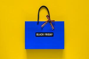 Blue shopping bag with ribbon and word at bag on yellow background for Black Friday shopping sale concept. photo