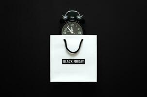 White shopping bag with Black Friday word and alarm clock inside for Black Friday shopping concept. photo