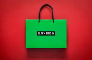 Green shopping bag with Black Friday word on red background for Black Friday shopping concept. photo