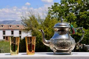 a silver tea pot and two glasses on a table photo