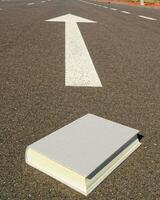 a book is sitting on the road with an arrow pointing to it photo