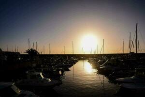 the sun is setting over a marina filled with boats photo