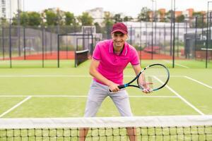 Male tennis player at the court looking happy photo