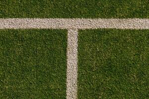 An empty green synthetic tennis court showing the sideline and net photo