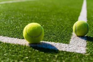 Green ball falling on floor nearly white lines of outdoor tennis court in public park photo