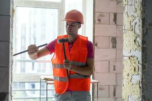 Young worker holding a hammer and a pointed chisel photo