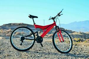 a red mountain bike is parked in the desert photo