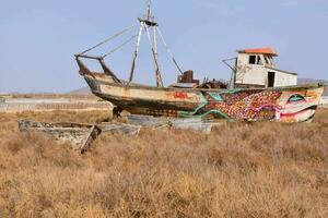 an old boat is sitting in the middle of a dry field photo