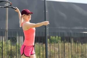 Woman playing tennis holding a racket and smiling photo