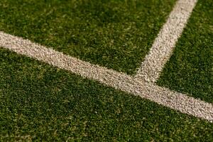 An empty green synthetic tennis court showing the sideline and net photo