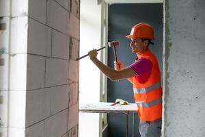 Young worker holding a hammer and a pointed chisel photo