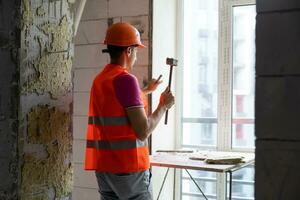 Young worker holding a hammer and a pointed chisel photo