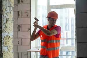 Young worker holding a hammer and a pointed chisel photo