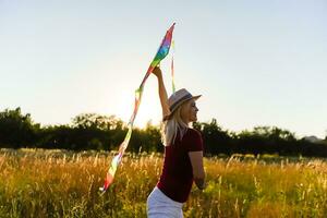 Portrait of a young and carefree woman launching kite on the greenfield. Concept of active lifestyle in nature photo