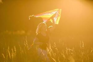 Portrait of a young and carefree woman launching kite on the greenfield. Concept of active lifestyle in nature photo