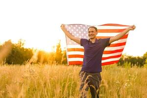 Fourth of July. Patriotic man with the national American flag in the field. Young man proudly waving an American flag. Independence Day. photo