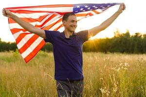 Fourth of July. Patriotic man with the national American flag in the field. Young man proudly waving an American flag. Independence Day. photo