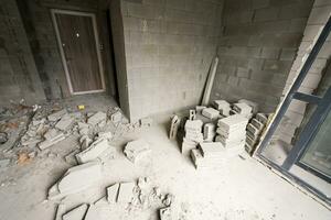 descanso el pared para renovación y construir el puerta para Entrada de edificio. carretilla con roto ladrillos en sitio construcción. foto