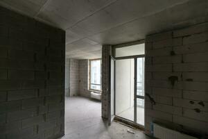 A new unfinished apartment room with the bare brick walls without decoration. photo