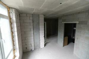 Small apartment without repair in a new building. A room in an unfinished house. Walls of foam block and concrete floor in a tiny apartment. photo