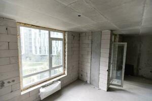 A new unfinished apartment room with the bare brick walls without decoration. photo