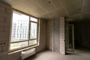 Small apartment without repair in a new building. A room in an unfinished house. Walls of foam block and concrete floor in a tiny apartment. photo