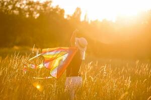 Portrait of a young and carefree woman launching kite on the greenfield. Concept of active lifestyle in nature photo