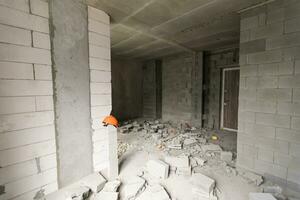 descanso el pared para renovación y construir el puerta para Entrada de edificio. carretilla con roto ladrillos en sitio construcción. foto