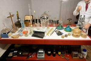 a man in a lab coat is standing in front of a table with various items photo
