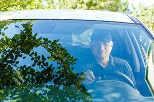 Smiling happy elderly senior man in the new car photo