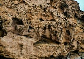 a rock face with many holes and cracks photo