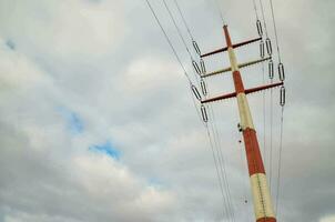 a tall pole with wires and clouds in the background photo