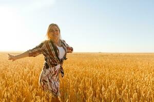 A girl in the midst of wheat spikelets. Caucasian woman posing with spikelets outside. photo