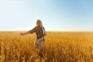 Woman in a wheat field on the background of the setting sun photo