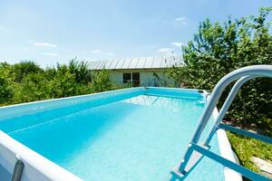 Escalera de barras de apoyo en la piscina azul foto