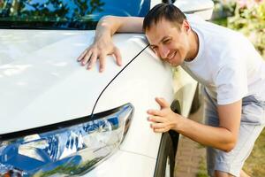 Man hugging on a car in a car dealership photo