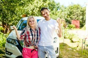 portrait of happy beautiful couple standing near the car photo