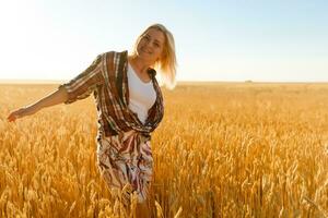 Woman in a wheat field on the background of the setting sun photo