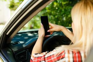 Young woman looks at her smartphone in a car. photo