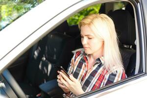 Young female driver using touch screen smartphone and gps navigation in a car. photo