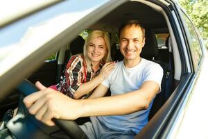 Happy young man and woman in a car enjoying a road trip on a summer day. photo