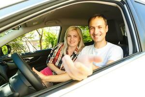 Happy young man and woman in a car enjoying a road trip on a summer day. photo